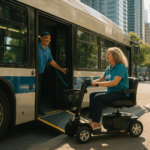 Image of a low-floor city bus with ramp deployed, as a middle-aged woman on a black mobility scooter boards confidently. A cheerful bus driver in a blue polo assists her. The scene is set in a bustling downtown area.